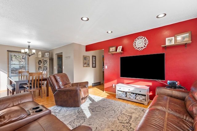 living room featuring an accent wall, baseboards, recessed lighting, an inviting chandelier, and wood finished floors