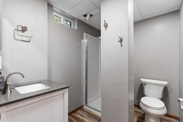 bathroom featuring a shower stall, toilet, wood finished floors, and baseboards