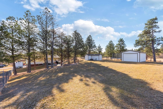 view of yard featuring an outbuilding, fence, and a detached garage