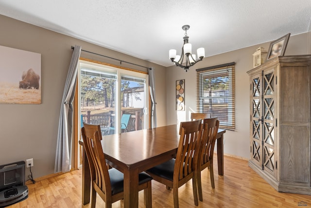 dining room featuring an inviting chandelier, light wood-style flooring, a healthy amount of sunlight, and a textured ceiling