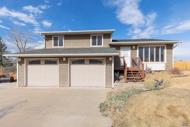 split level home featuring a garage, concrete driveway, roof with shingles, and fence