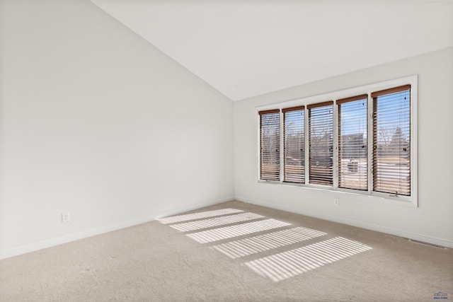 empty room with carpet floors, baseboards, visible vents, and vaulted ceiling