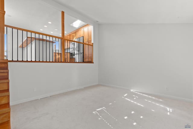 carpeted empty room featuring recessed lighting, stairway, baseboards, and vaulted ceiling with skylight