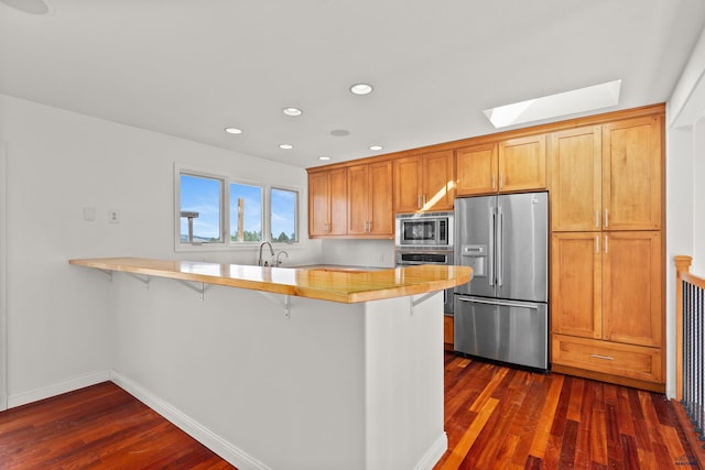 kitchen featuring stainless steel appliances, a peninsula, a skylight, and light countertops