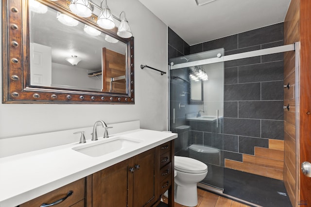 bathroom featuring tiled shower, toilet, wood finished floors, and vanity