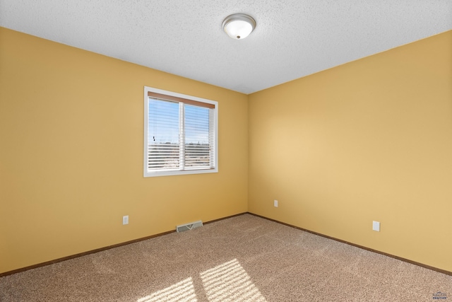 empty room with visible vents, baseboards, carpet, and a textured ceiling