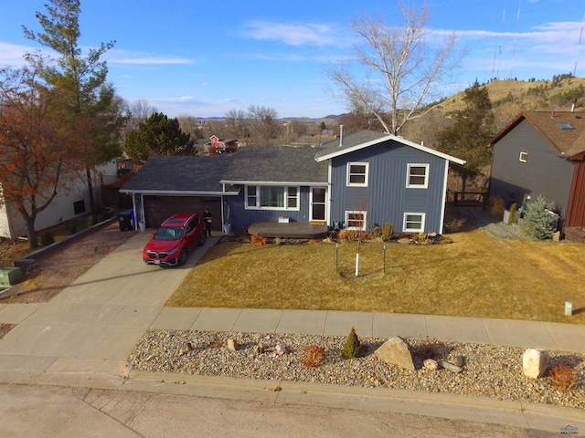 split level home featuring a mountain view, driveway, an attached garage, and a front yard