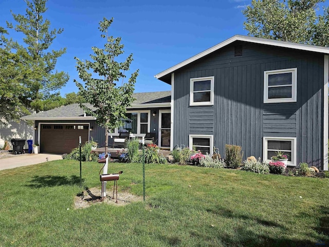 split level home featuring an attached garage, concrete driveway, a front yard, and roof with shingles