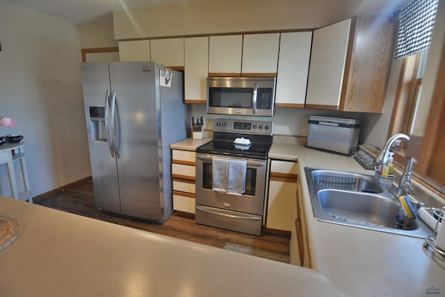 kitchen featuring dark wood-style flooring, a sink, stainless steel appliances, light countertops, and white cabinets