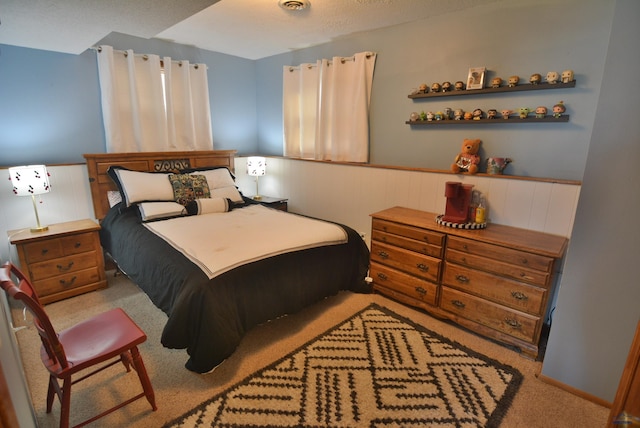 bedroom with a wainscoted wall, visible vents, and carpet