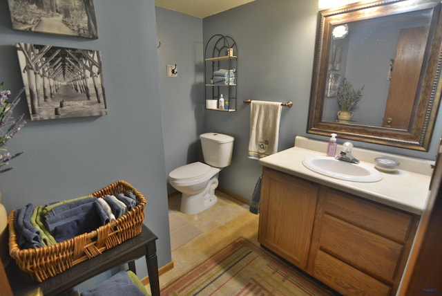 half bath featuring baseboards, toilet, and vanity