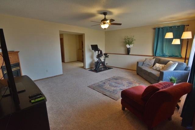 living room featuring a glass covered fireplace, baseboards, carpet floors, and ceiling fan