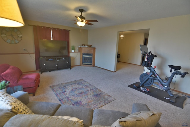 living area with light carpet, a glass covered fireplace, a ceiling fan, and baseboards