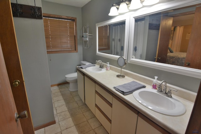 bathroom featuring double vanity, toilet, and a sink