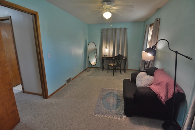 sitting room with visible vents, carpet floors, baseboards, and a ceiling fan