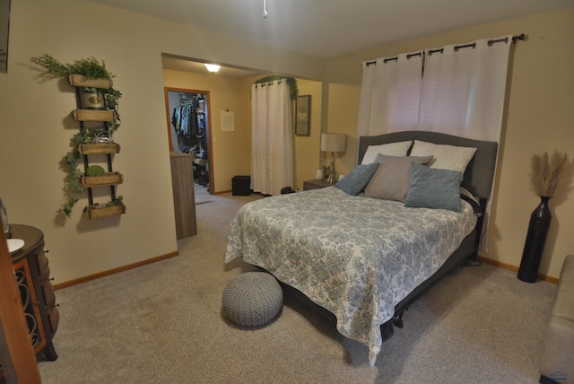 bedroom with a spacious closet, carpet, and baseboards