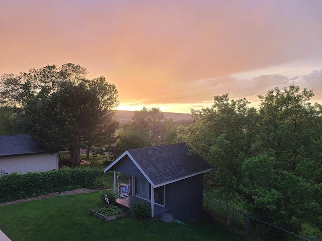 outdoor structure at dusk featuring an outdoor structure, fence, a lawn, and a shed