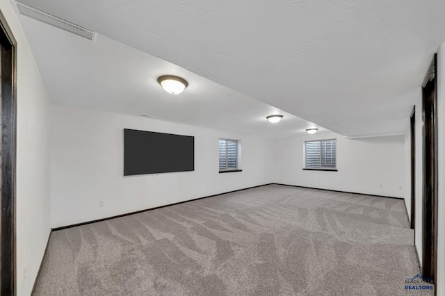 basement featuring carpet flooring, baseboards, and visible vents