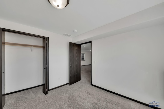 unfurnished bedroom featuring baseboards, visible vents, a closet, and light carpet