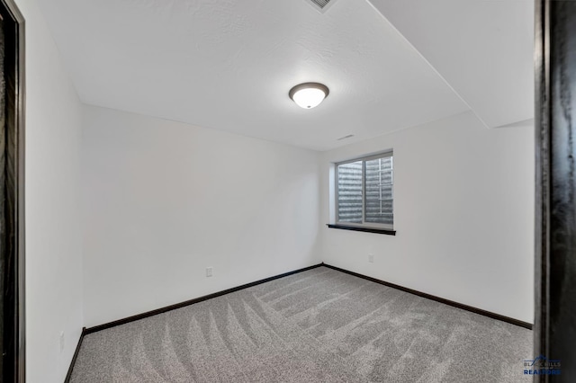 carpeted empty room featuring baseboards