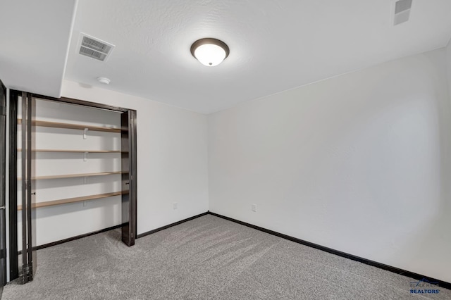 unfurnished bedroom with visible vents, baseboards, a textured ceiling, and carpet flooring