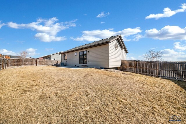 back of house featuring central AC unit, a lawn, and a fenced backyard