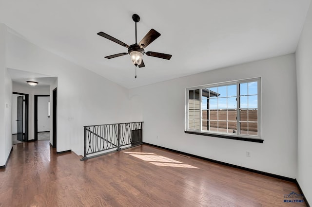 spare room with visible vents, lofted ceiling, wood finished floors, baseboards, and ceiling fan