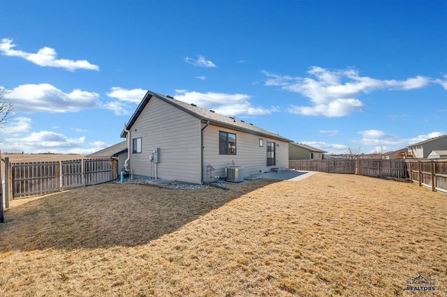 rear view of property featuring cooling unit, a lawn, and a fenced backyard