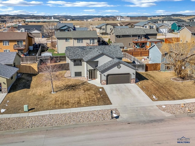 view of front facade featuring a garage, a residential view, driveway, and fence