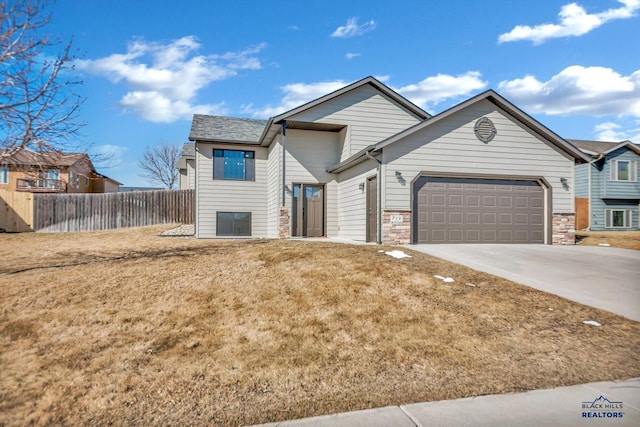 view of front of house featuring a front lawn, stone siding, fence, concrete driveway, and a garage