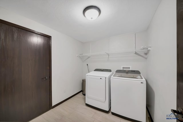 washroom with baseboards, independent washer and dryer, and laundry area