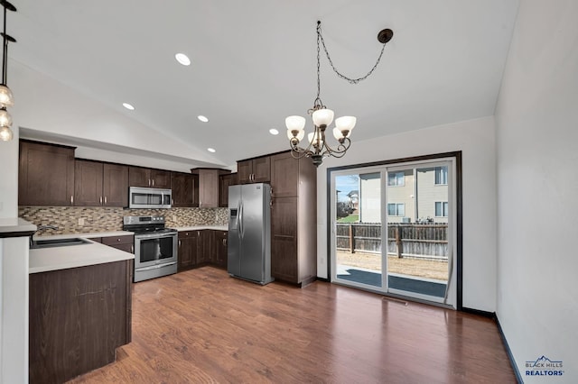 kitchen featuring wood finished floors, dark brown cabinetry, appliances with stainless steel finishes, decorative backsplash, and vaulted ceiling