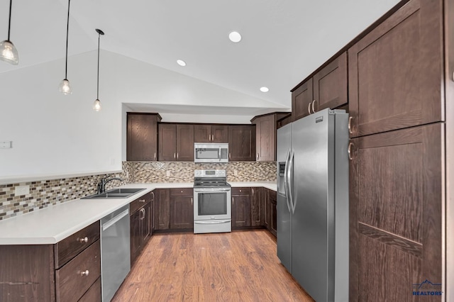 kitchen with light wood-type flooring, a sink, dark brown cabinetry, appliances with stainless steel finishes, and lofted ceiling