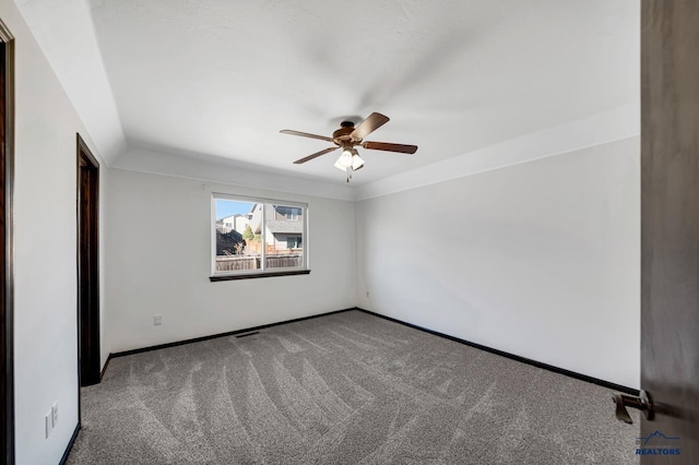 carpeted spare room featuring baseboards and ceiling fan