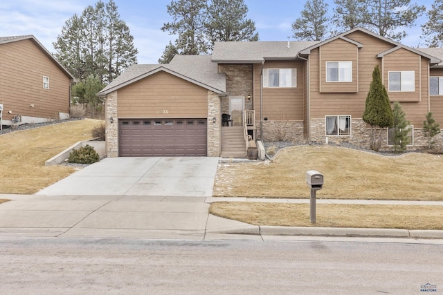 view of front of home featuring a shingled roof, concrete driveway, a front yard, stone siding, and an attached garage