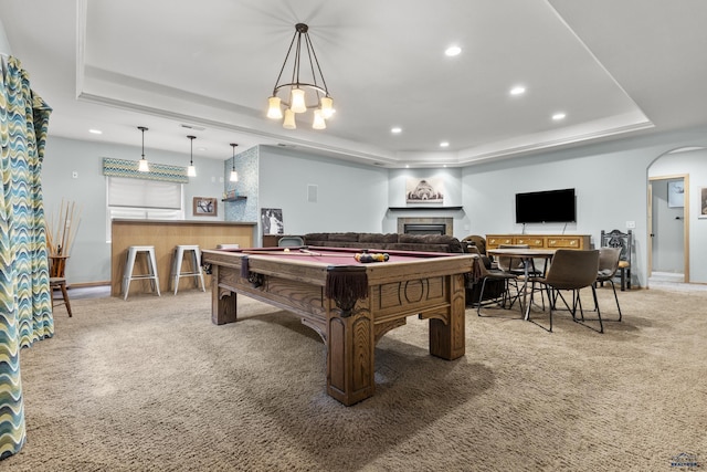 recreation room featuring carpet floors, recessed lighting, a fireplace, arched walkways, and a raised ceiling