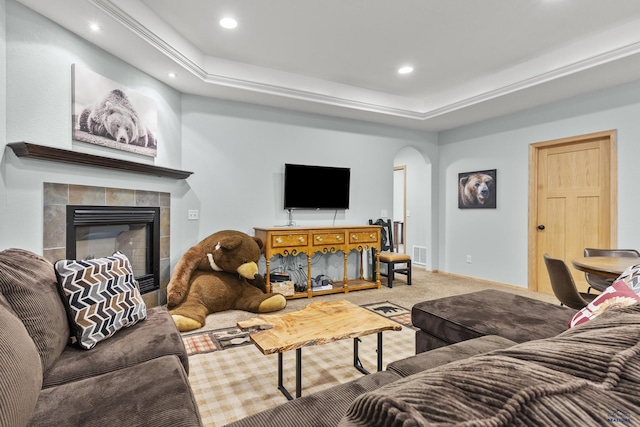 carpeted living room with visible vents, baseboards, a tiled fireplace, recessed lighting, and arched walkways