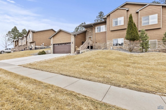 view of front of house featuring stone siding, driveway, a front lawn, and a garage