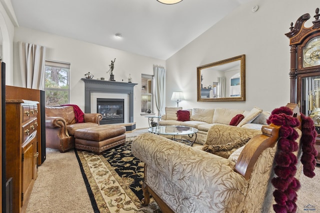 living area featuring a glass covered fireplace, lofted ceiling, and light carpet