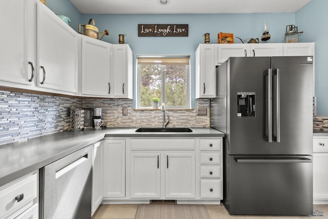 kitchen featuring backsplash, white cabinetry, stainless steel appliances, and a sink