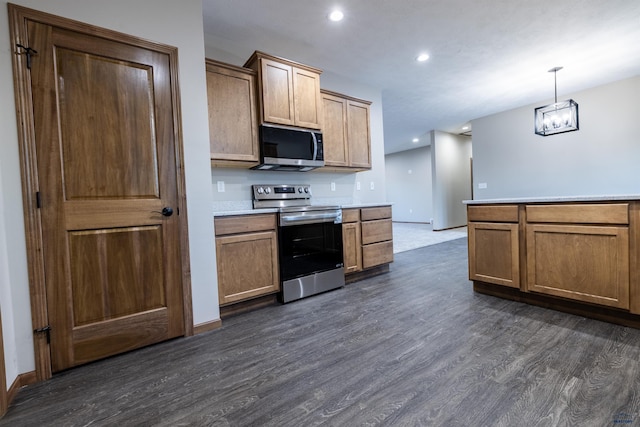 kitchen featuring recessed lighting, dark wood-type flooring, light countertops, appliances with stainless steel finishes, and pendant lighting