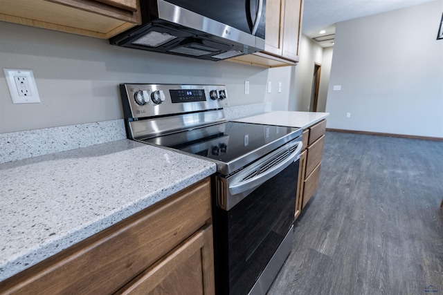 kitchen featuring dark wood finished floors, light stone countertops, baseboards, and appliances with stainless steel finishes