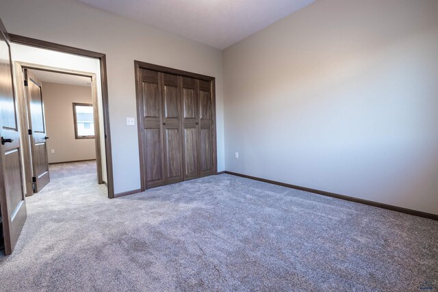 unfurnished bedroom with light colored carpet, baseboards, and a closet