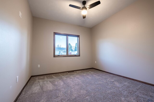 carpeted spare room with visible vents, baseboards, and ceiling fan