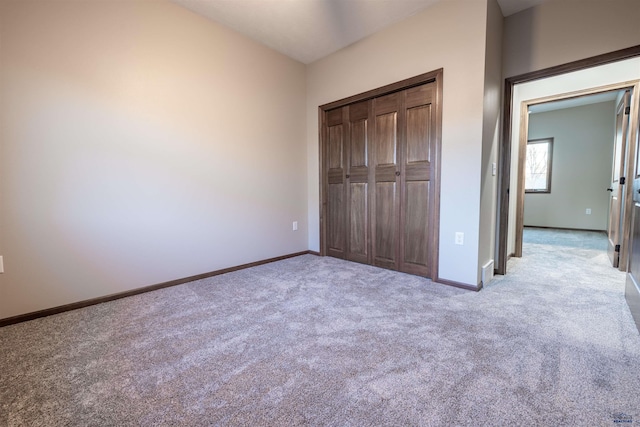 unfurnished bedroom with light carpet, a closet, and baseboards