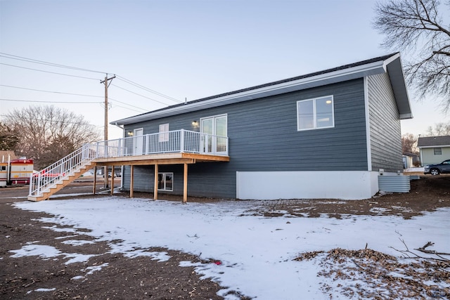 snow covered property with stairway and a wooden deck