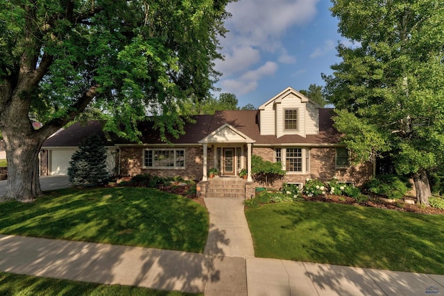 view of front of home with brick siding, an attached garage, and a front yard