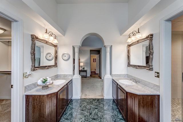 full bath featuring two vanities, decorative columns, and a sink