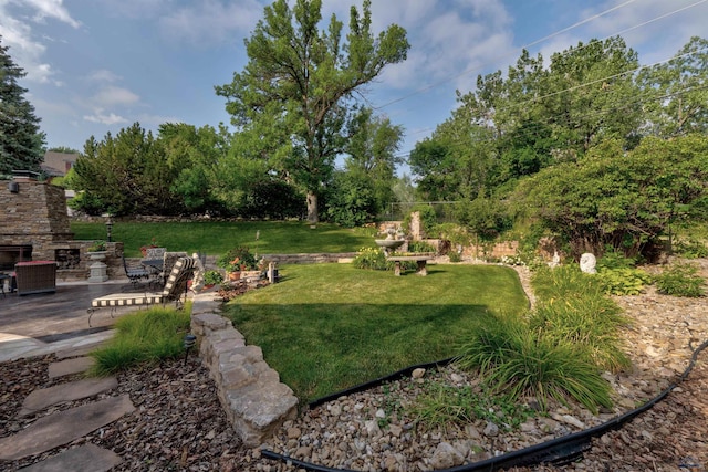 view of yard featuring an outdoor stone fireplace and a patio area