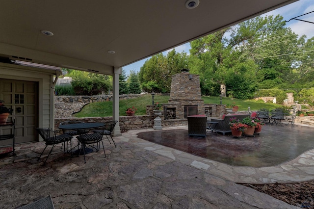 view of patio / terrace with outdoor dining space and an outdoor stone fireplace